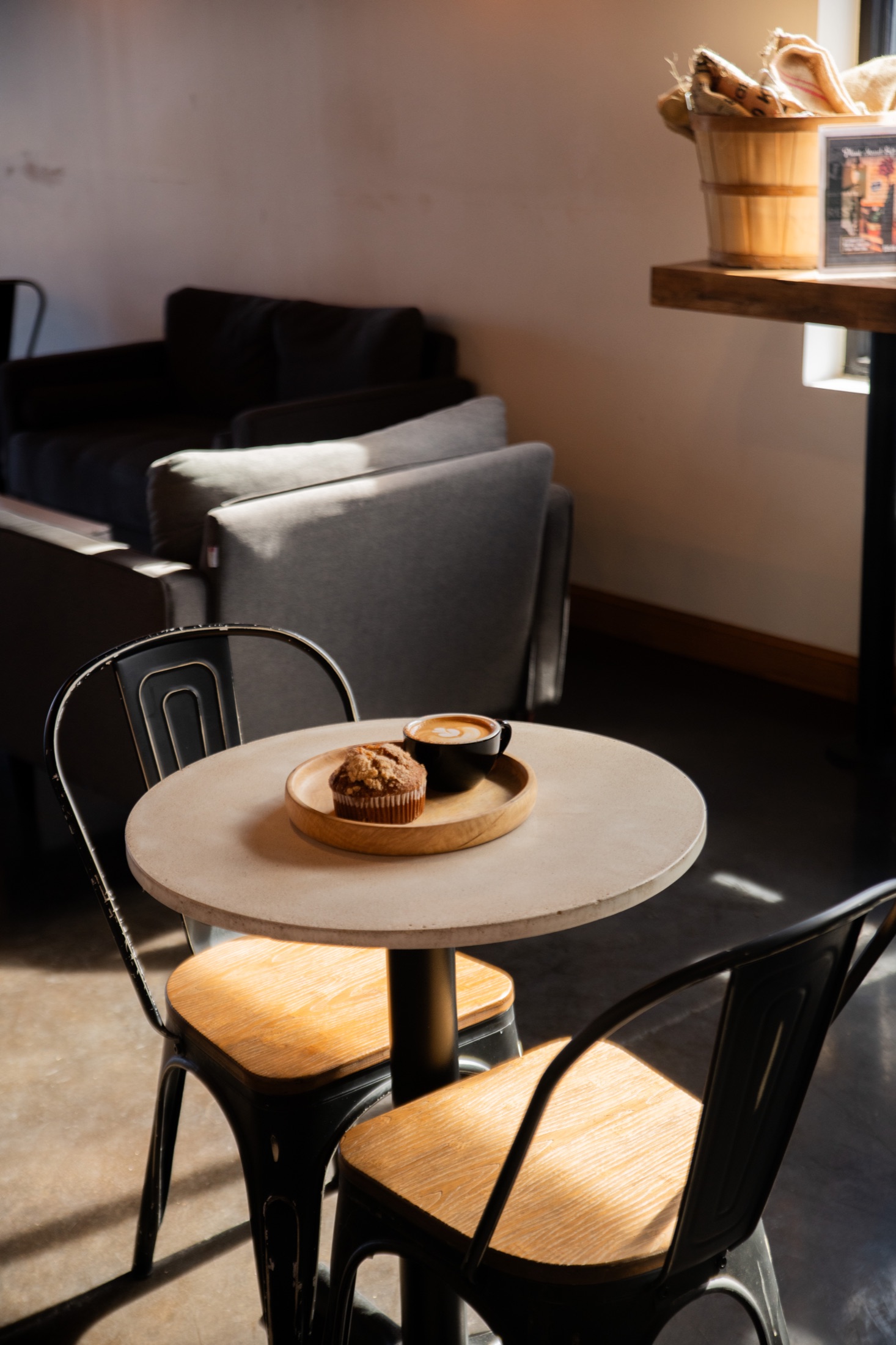 A sunlit café table set with coffee and a fresh muffin at OpenFlame